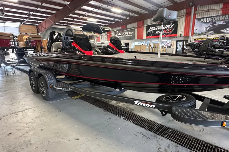 Slide: The Image of 2026 Triton 20XP Patriot boat in showroom, sleek black design, dual axle trailer. - 2