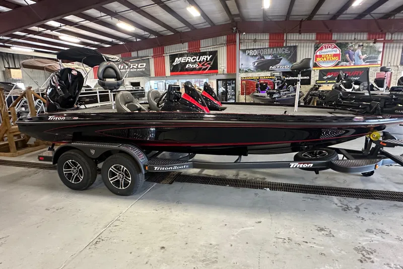 Slide: The Image of 2026 Triton 20XP Patriot boat in showroom, sleek design, dual-axle trailer, indoor display. - 1
