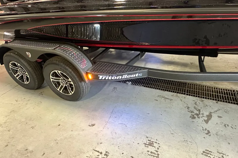 Slide: The Image of Trailer of 2026 Triton 20XP Patriot boat with dual wheels and sleek design. - 20