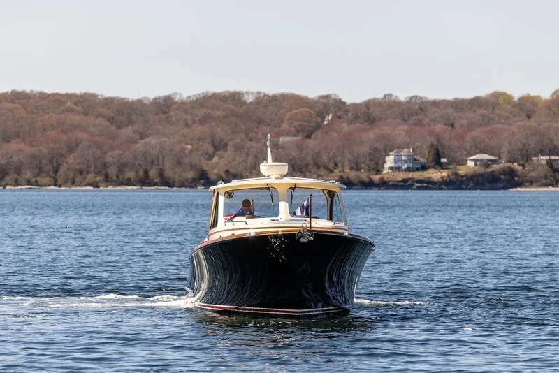 Slide: The Image of 2014 Hinckley Talaria 34 cruising on a serene lake with wooded shoreline backdrop. - 2