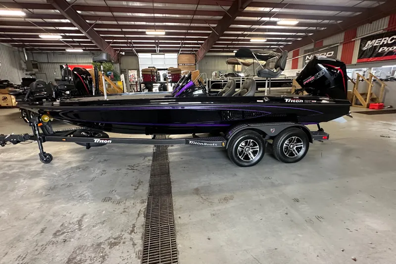 Slide: The Image of 2026 Triton 20XP Patriot boat in showroom, sleek design, dual-axle trailer. - 29