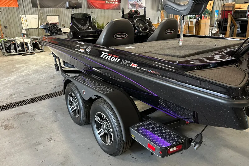 Slide: The Image of 2026 Triton 20XP Patriot boat in showroom, featuring sleek design and dual-axle trailer. - 15