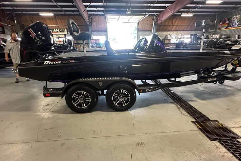 Slide: The Image of 2026 Triton 20XP Patriot boat on trailer in showroom, featuring sleek black design. - 28