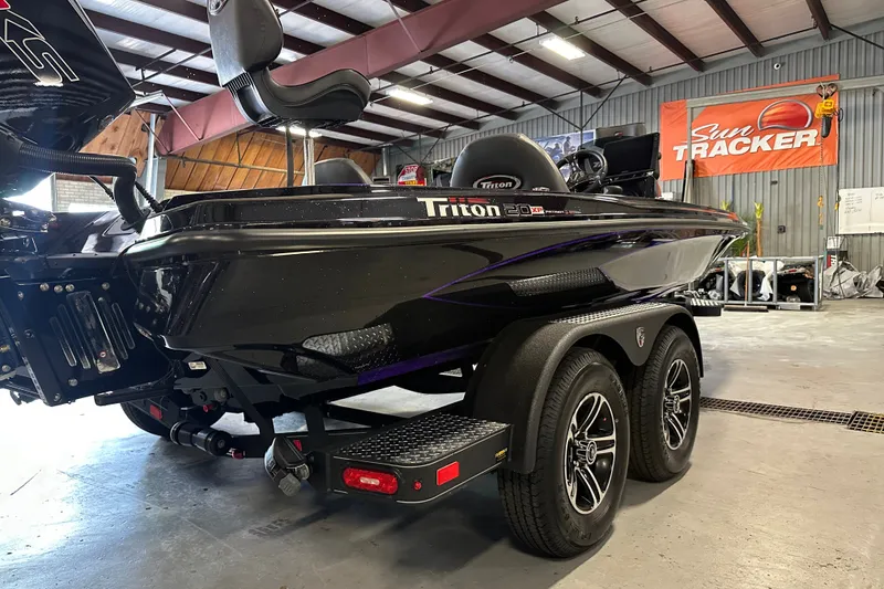 Slide: The Image of 2026 Triton 20XP Patriot boat in showroom, featuring sleek black design and dual-axle trailer. - 14