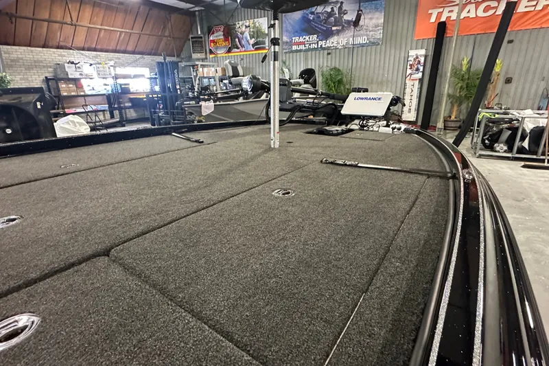 Slide: The Image of 2025 Triton 21XP Patriot boat interior with carpeted deck in showroom setting. - 8