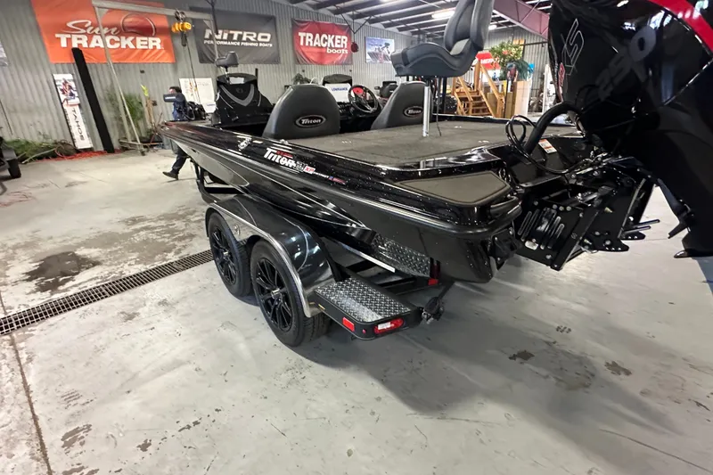 Slide: The Image of 2025 Triton 21XP Patriot boat in showroom, featuring sleek black design and dual-axle trailer. - 4