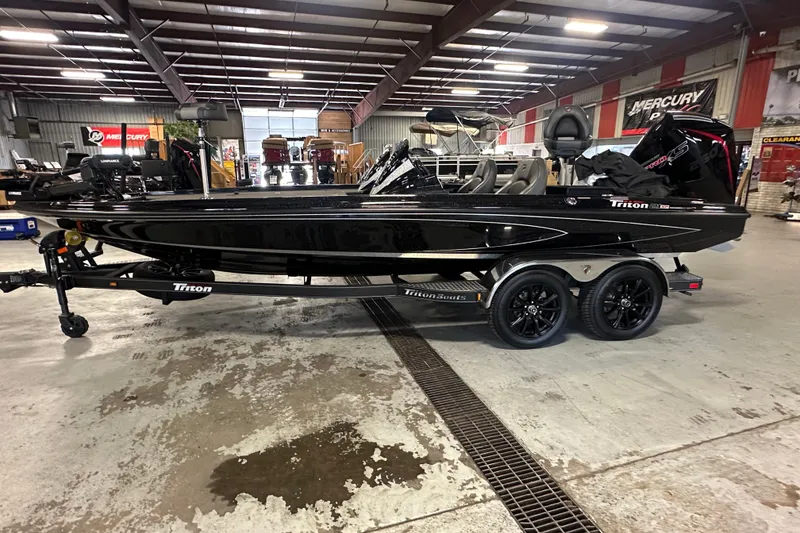 Slide: The Image of 2025 Triton 21XP Patriot boat in showroom, sleek black design, dual-axle trailer. - 1