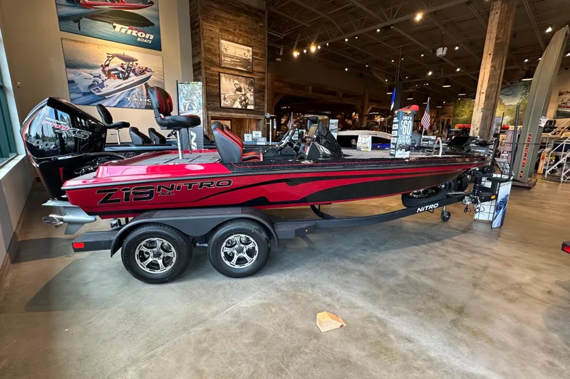 The Image of 2026 Nitro Z19 XL Pro boat displayed in showroom, red and black design, dual-axle trailer. - 0