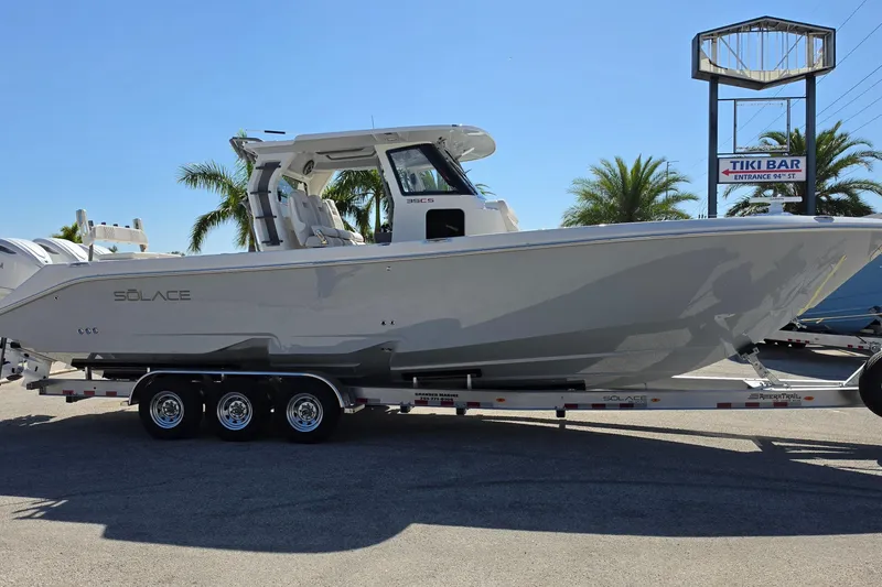Slide: The Image of 2026 Solace 35CS boat on trailer, parked near palm trees and a Tiki Bar sign. - 8
