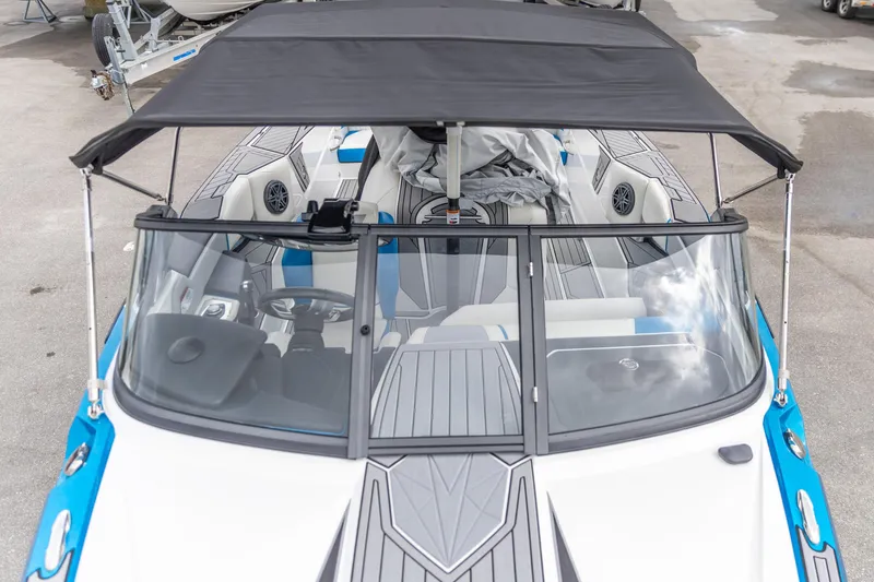 Slide: The Image of 2021 Nautique Ski Nautique boat with canopy, blue and white interior, and modern dashboard. - 12