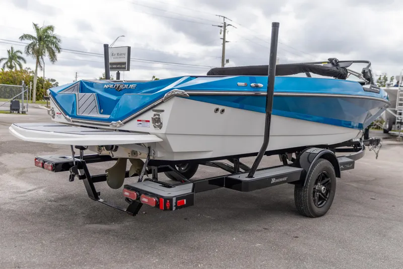 Slide: The Image of 2021 Nautique Ski Nautique boat on trailer, blue and white design, parked outdoors. - 15