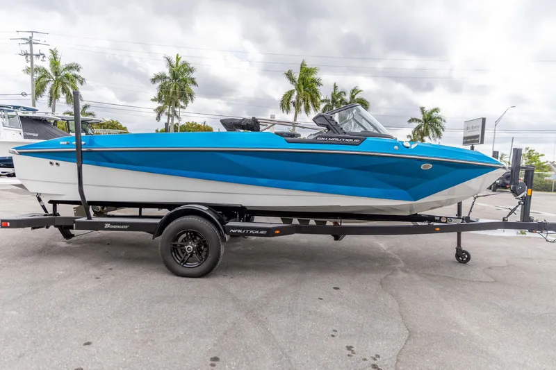Slide: The Image of 2021 Nautique Ski Nautique boat on trailer, blue and white, parked outdoors. - 16
