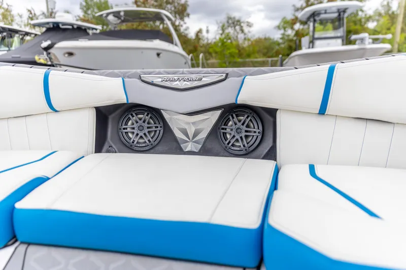 Slide: The Image of 2021 Nautique Ski Nautique boat interior with white and blue seating and built-in speakers. - 4