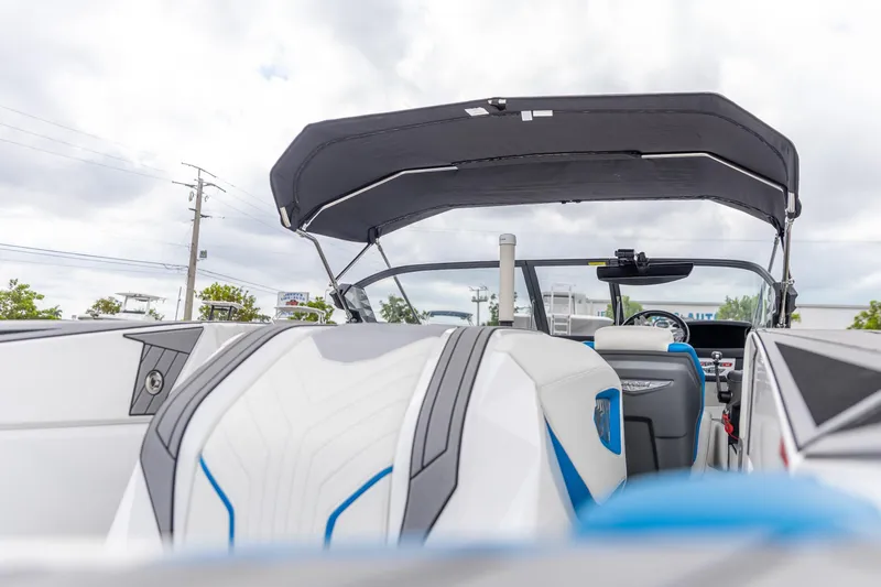 Slide: The Image of 2021 Nautique Ski Nautique boat interior with modern seating and canopy under cloudy sky. - 8