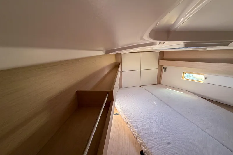 Slide: The Image of Interior cabin of 2022 Beneteau Oceanis 40.1 yacht, featuring a cozy bed and wooden accents. - 11