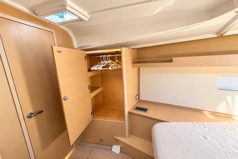 Slide: The Image of Interior of 2022 Beneteau Oceanis 40.1 yacht, featuring a wooden wardrobe and cozy cabin space. - 22