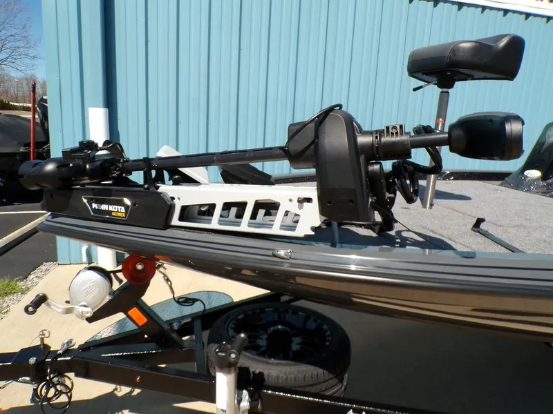 Slide: The Image of 2025 Phoenix 920 Elite boat with trolling motor, parked on a trailer near a blue building. - 28
