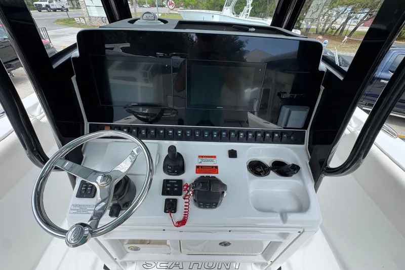 Slide: The Image of 2020 Sea Hunt Gamefish 30 helm with steering wheel, controls, and navigation screens. - 30