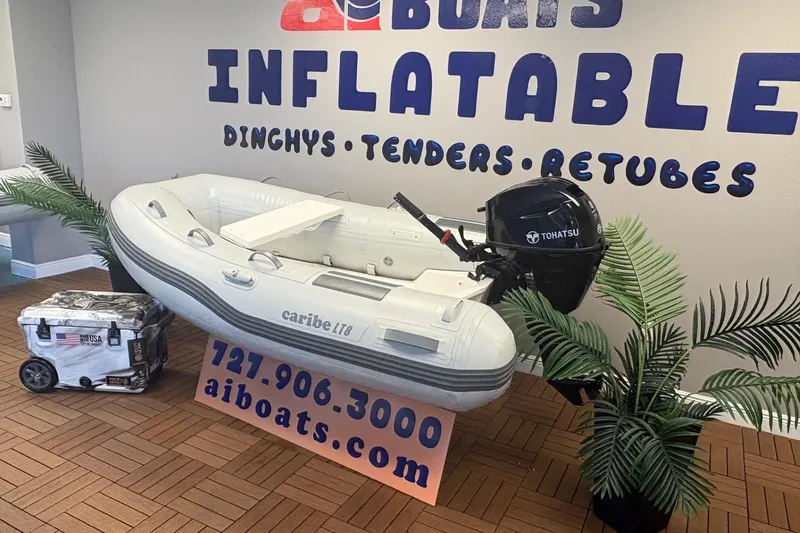 Slide: The Image of Inflatable Caribe L-8 boat with Tohatsu motor displayed indoors, 2026 model. - 2
