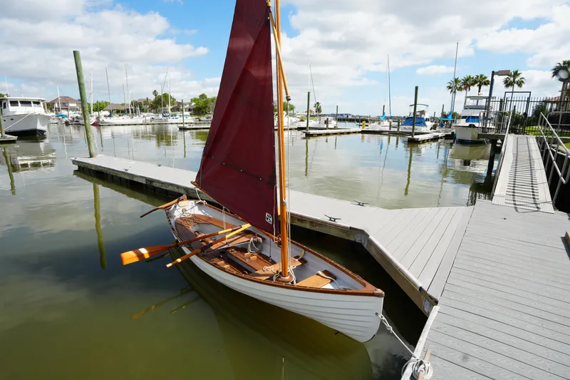 The Image of Sailboat Whitehall Spirit 19, 2006 model, docked at a marina under a partly cloudy sky. - 1