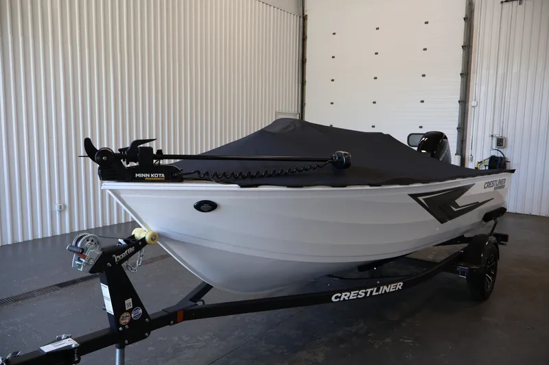 Slide: The Image of 2026 Crestliner 1650 Kodiak SC boat with cover, displayed indoors on a trailer. - 46