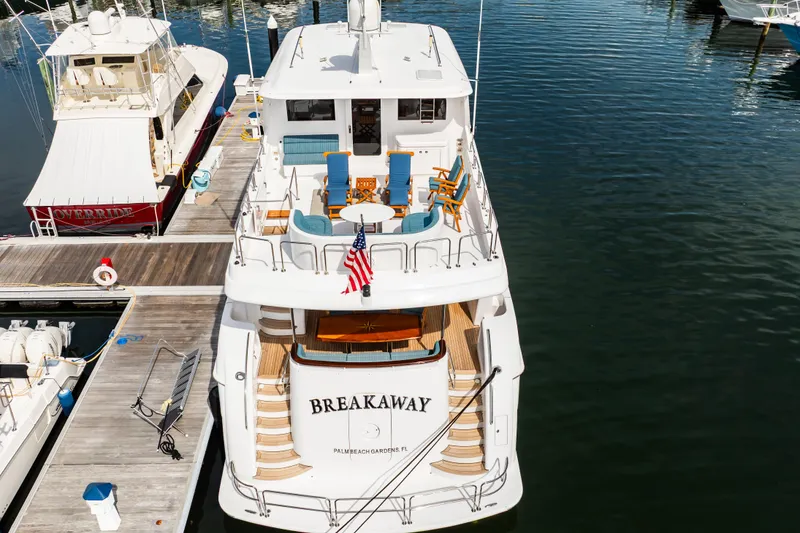 Slide: The Image of 2012 Hatteras 80 Motor Yacht docked, featuring spacious deck and American flag. - 10