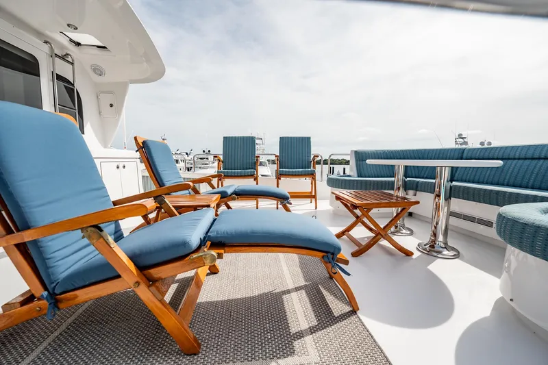Slide: The Image of Spacious deck of 2012 Hatteras 80 Motor Yacht with blue cushioned seating and wooden tables. - 38