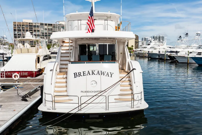 Slide: The Image of 2012 Hatteras 80 Motor Yacht docked, rear view with "Breakaway" name and American flag. - 4