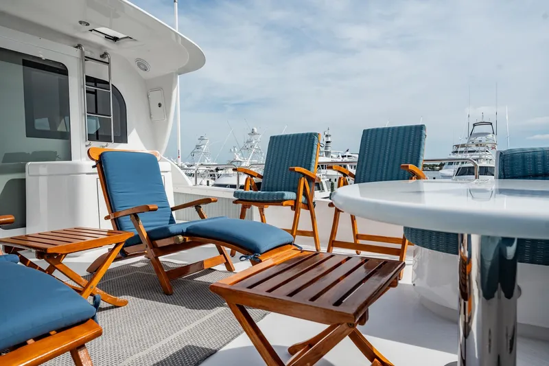 Slide: The Image of Luxurious deck seating on a 2012 Hatteras 80 Motor Yacht, featuring blue cushioned chairs. - 41