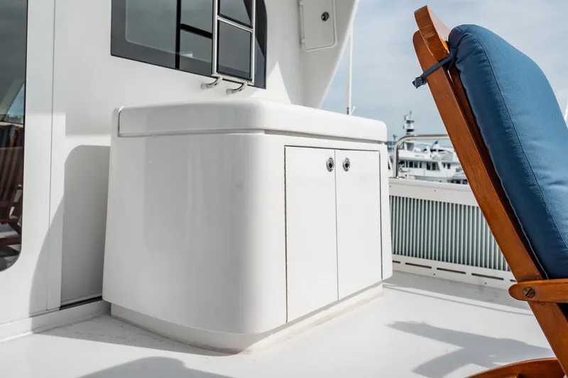 Slide: The Image of Hatteras 80 Motor Yacht 2012 deck with white cabinet and blue cushioned chair. - 49