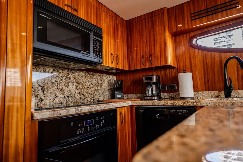 Slide: The Image of Luxurious kitchen interior of 2012 Hatteras 80 Motor Yacht with granite countertops and wood cabinetry. - 80