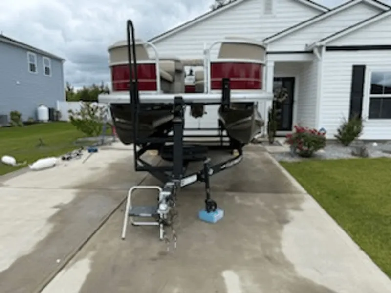 Slide: The Image of 2024 Sun Tracker PARTY BARGE on a trailer in front of a house. - 8