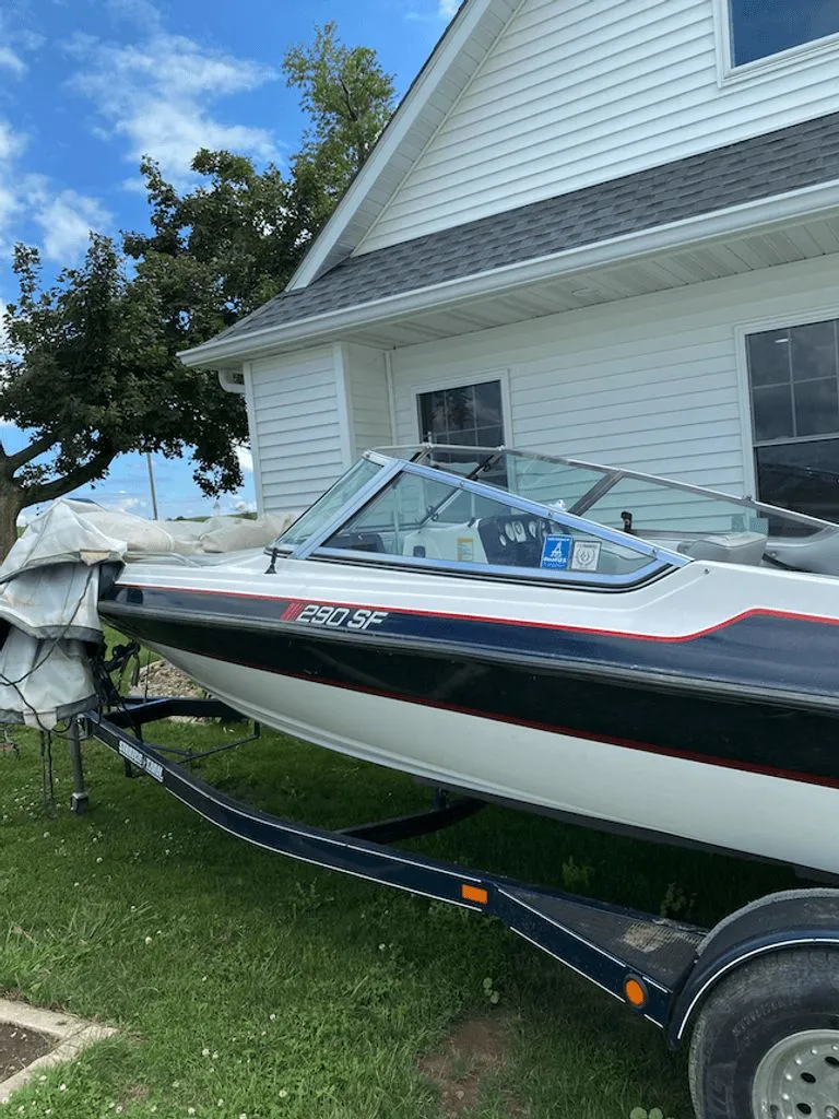 The Image of 1997 Stratos 290 SF boat parked by a white house. - 0