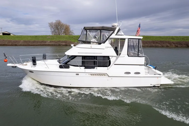 The Image of 2000 Carver 404 Cockpit Motor Yacht cruising on a river under cloudy skies. - 0