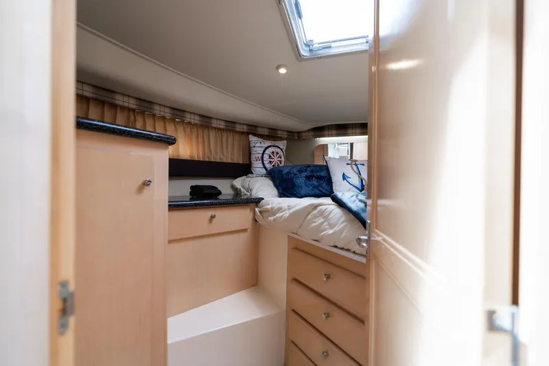 Slide: The Image of Interior cabin of 2000 Carver 404 Cockpit Motor Yacht, featuring cozy bedding and storage. - 12