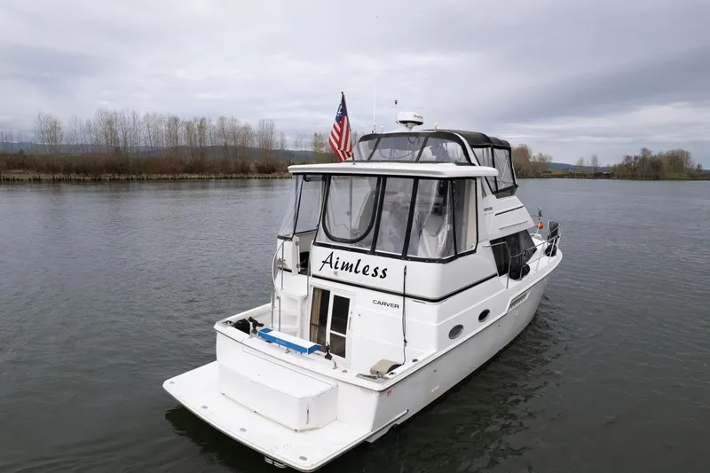 Slide: The Image of 2000 Carver 404 Cockpit Motor Yacht on calm water, rear view with American flag. - 3