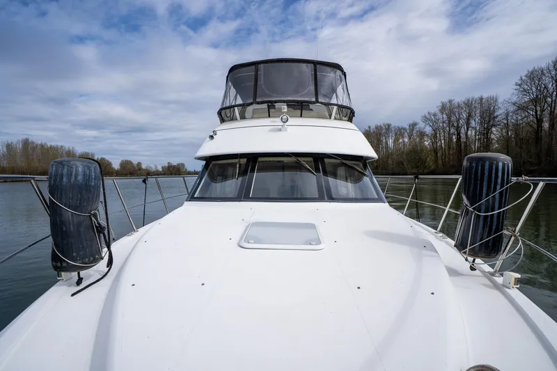 Slide: The Image of 2000 Carver 404 Cockpit Motor Yacht on a serene river with cloudy sky. - 33