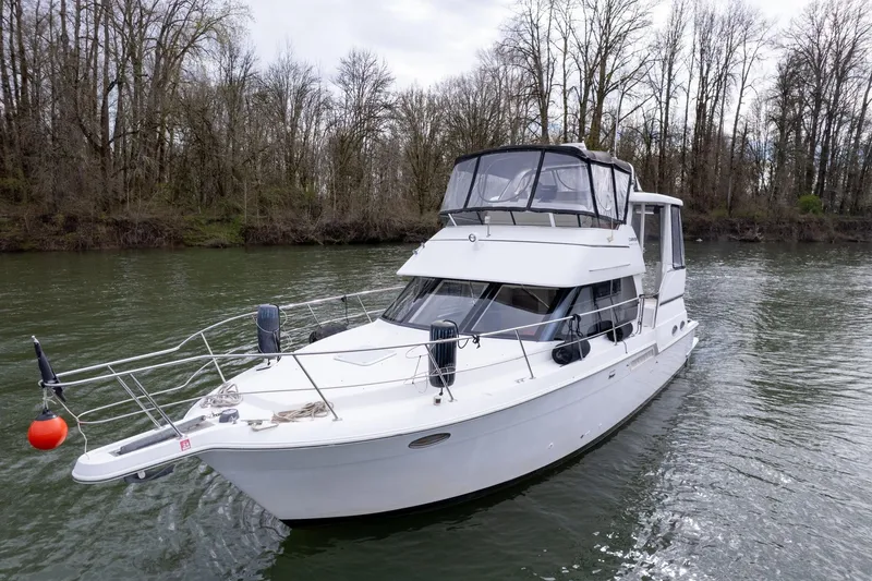Slide: The Image of 2000 Carver 404 Cockpit Motor Yacht cruising on a serene river with forested banks. - 35