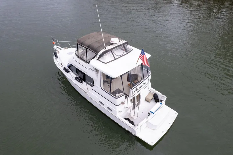 Slide: The Image of 2000 Carver 404 Cockpit Motor Yacht on calm water, featuring a spacious deck and American flag. - 40