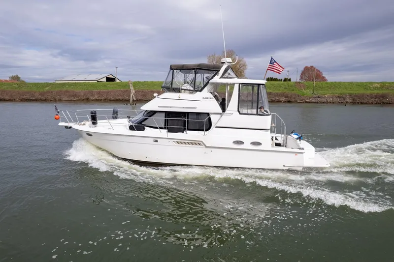 Slide: The Image of 2000 Carver 404 Cockpit Motor Yacht cruising on a river under cloudy skies. - 41