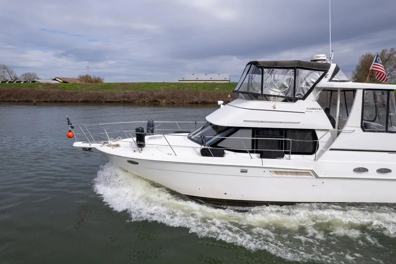 Slide: The Image of 2000 Carver 404 Cockpit Motor Yacht cruising on a river under cloudy skies. - 42