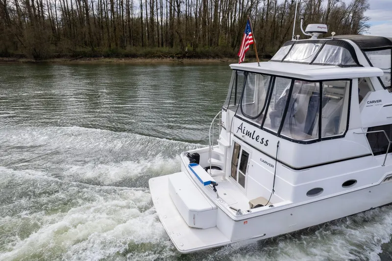 Slide: The Image of 2000 Carver 404 Cockpit Motor Yacht cruising on a river, American flag displayed. - 43