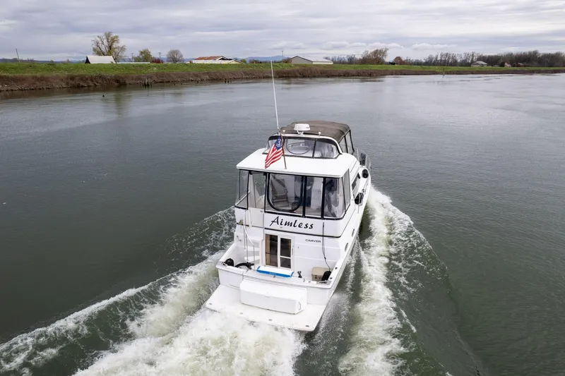 Slide: The Image of 2000 Carver 404 Cockpit Motor Yacht cruising on a calm river. - 44
