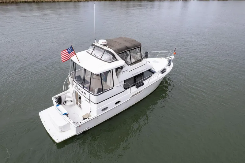 Slide: The Image of 2000 Carver 404 Cockpit Motor Yacht on calm water, displaying an American flag. - 46