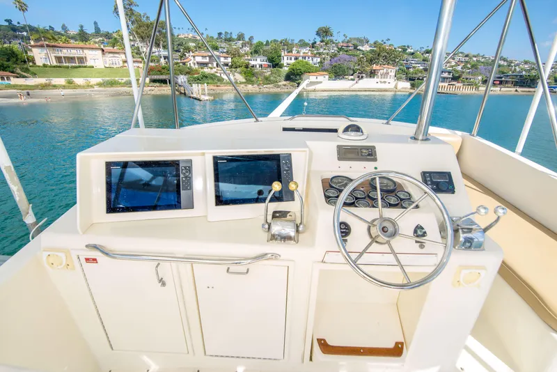 Slide: The Image of Helm of 1986 Ocean Yachts 48 Super Sport overlooking scenic waterfront homes. - 11