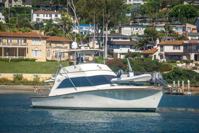 Slide: The Image of 1986 Ocean Yachts 48 Super Sport yacht anchored near coastal homes. - 2