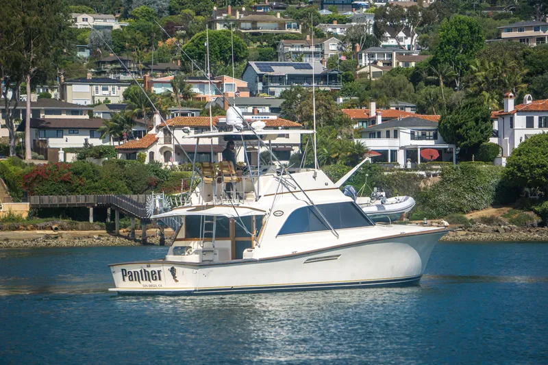 Slide: The Image of 1986 Ocean Yachts 48 Super Sport boat on water, with scenic residential backdrop. - 4