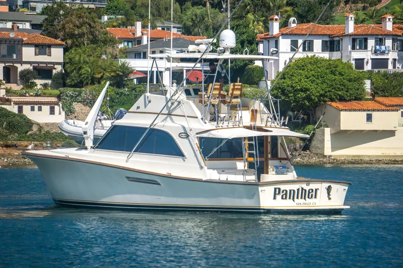 Slide: The Image of 1986 Ocean Yachts 48 Super Sport boat named "Panther" docked near waterfront homes. - 5