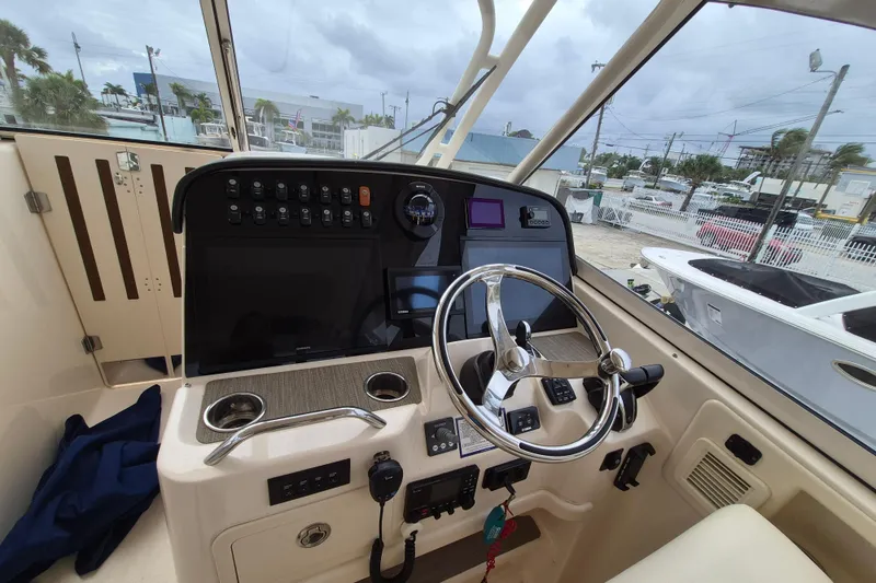 Slide: The Image of Helm of 2022 Grady-White Freedom 335 boat with steering wheel and control panel. - 11