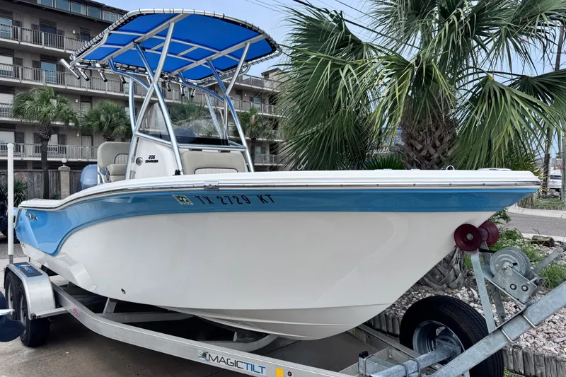 The Image of 2018 Sea Fox 206 Commander boat on trailer, blue and white, near palm trees. - 0